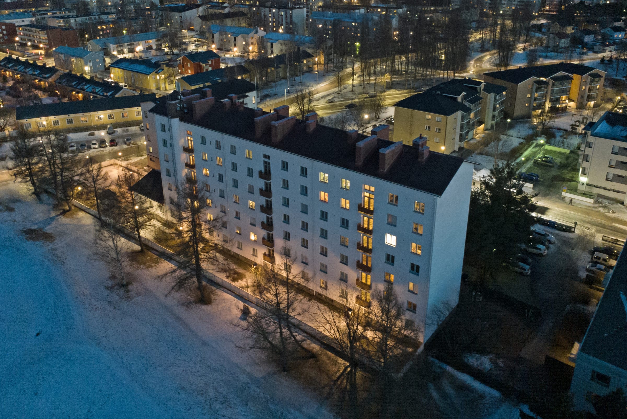 Kerrostalo ja ympäröivät korttelit talvi-illan valossa Oulussa.