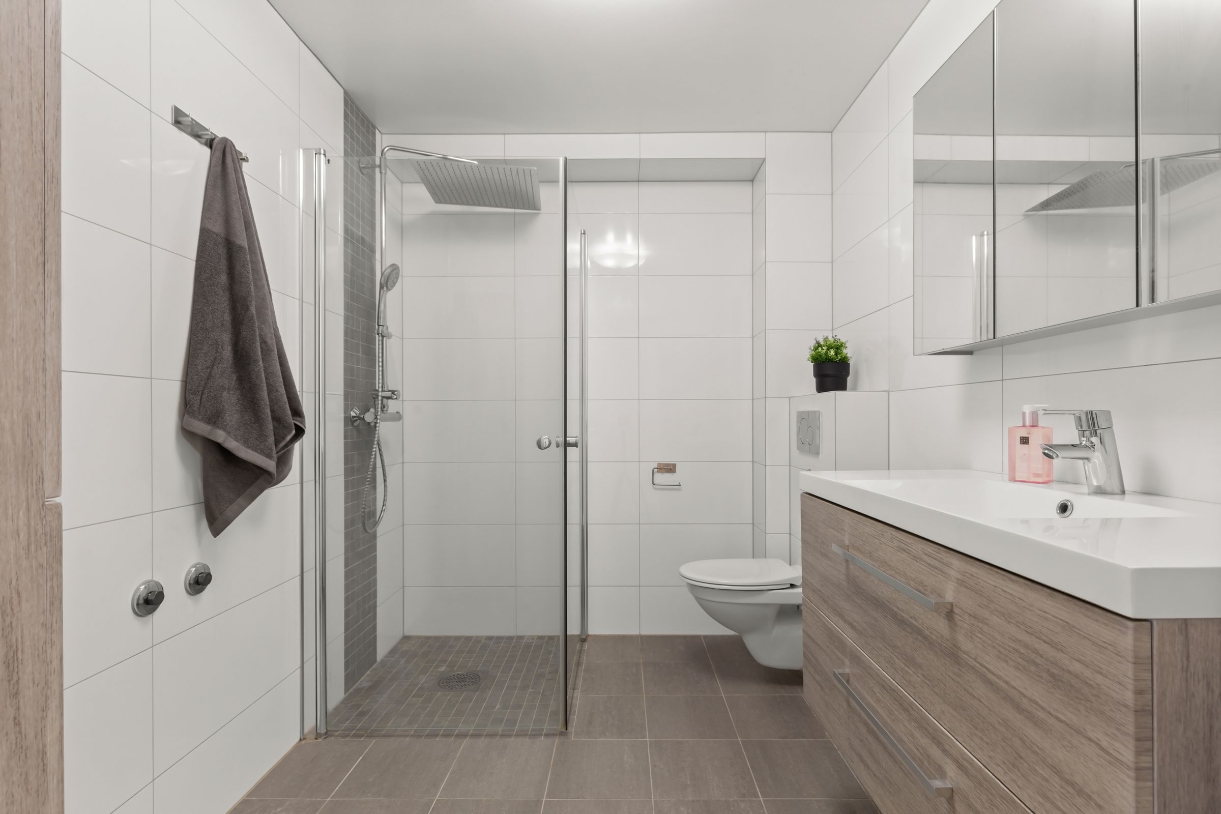 Remontoitu märkätila, jossa lasiseinäinen suihkunurkkaus, seinä-wc ja allaskaluste