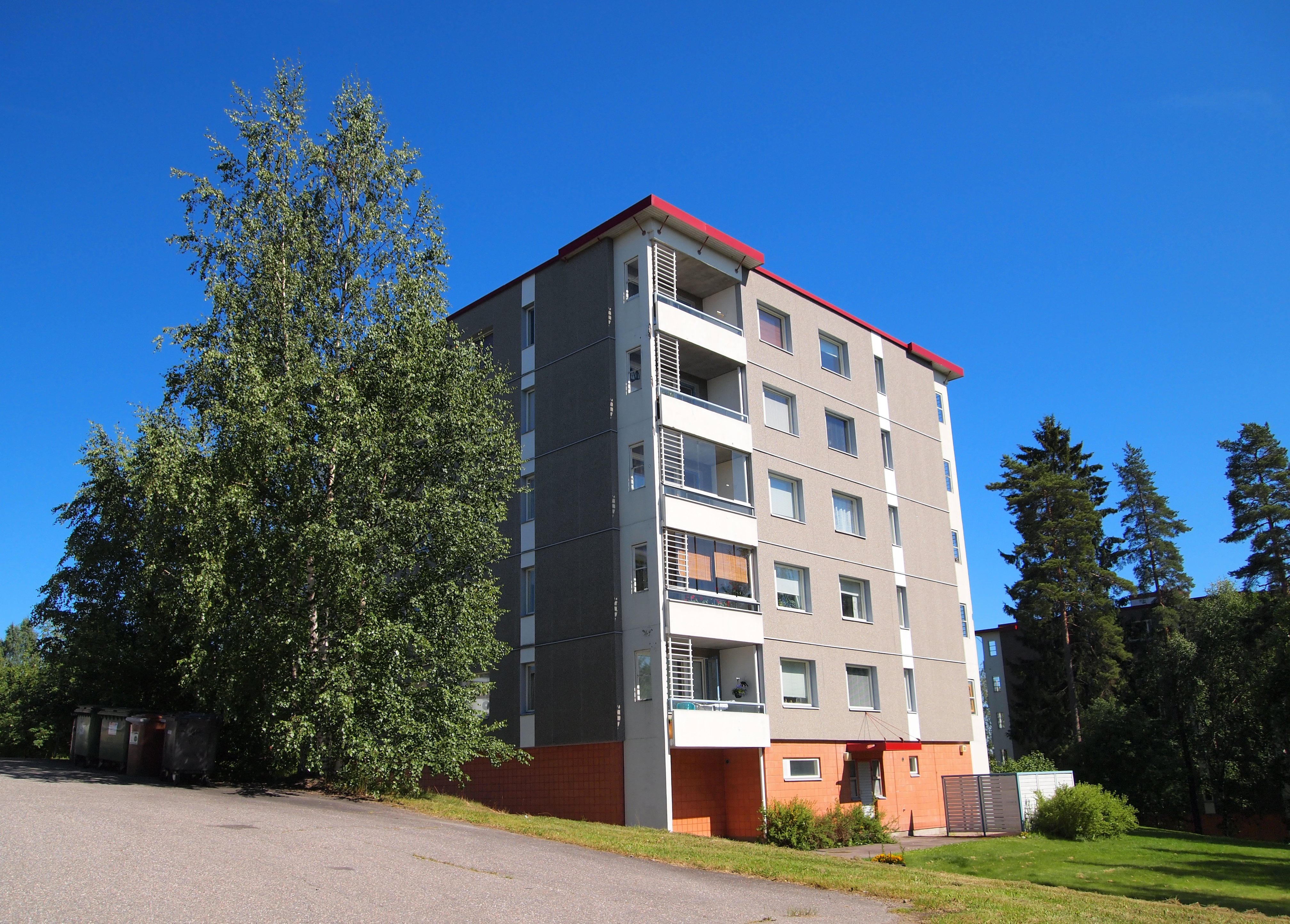 Kerrostalon pääty Lahden Liipolassa, jossa tiiliverhoiltu sokkeli rajautuu nurmikkoon