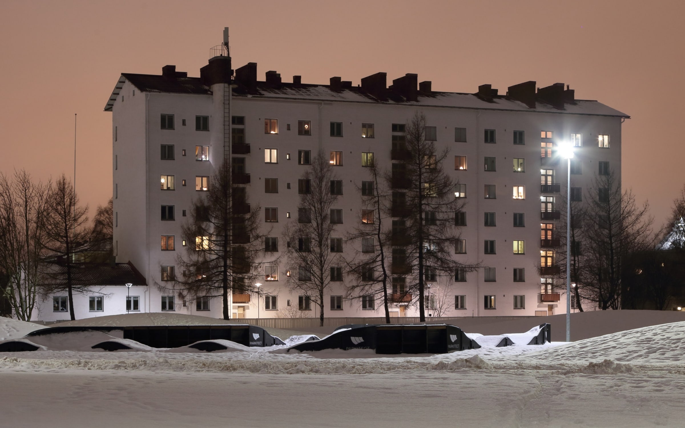 Kerrostalo Oulun Nuottalassa joulukuun iltahämärässä. Hallituksen palkkioista päättää taloyhtiön yhtiökokous.