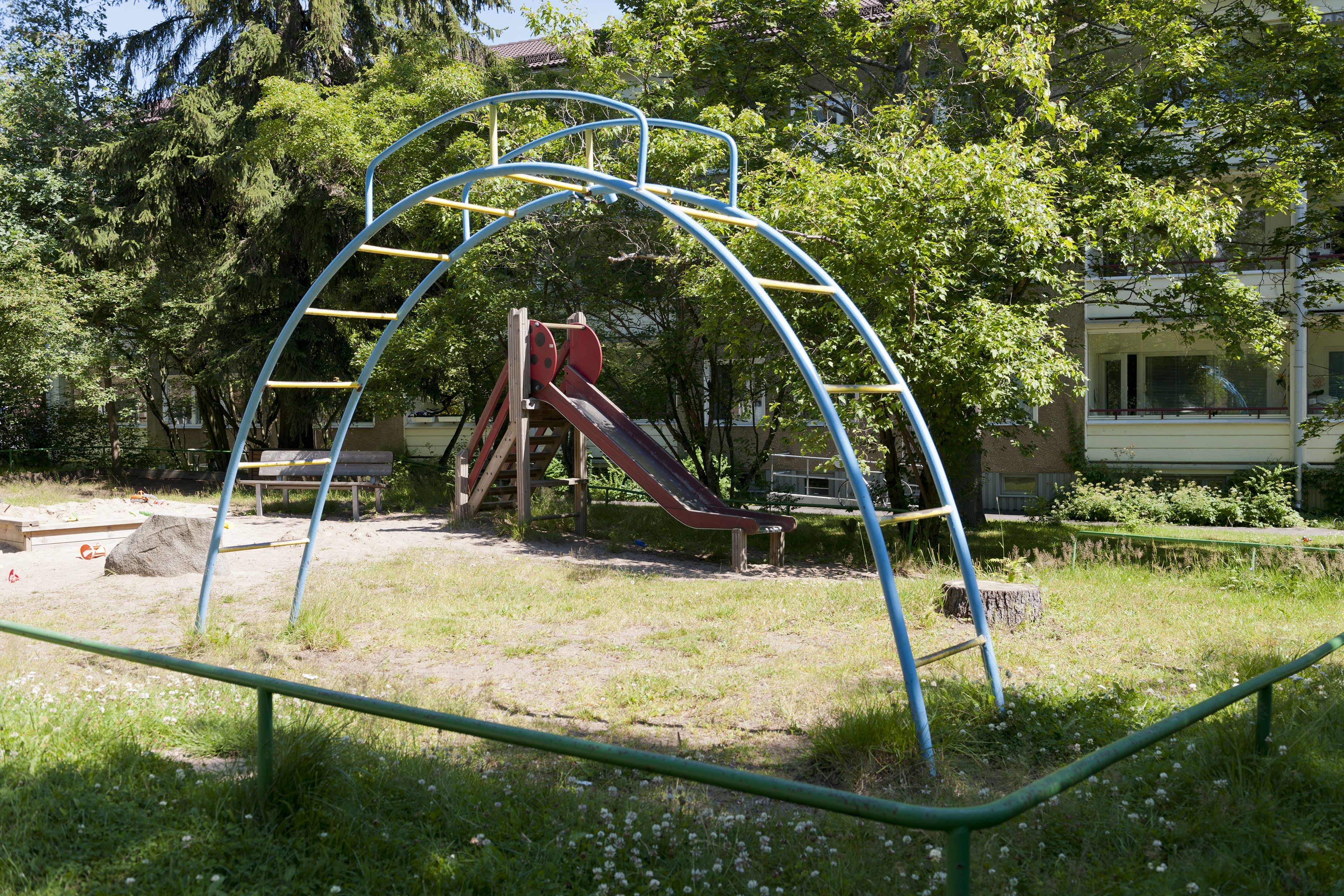Kerrostalopihan leikkialue Helsingin Maunulassa, jossa kiipeilyteline, liukumäki ja hiekkalaatikko