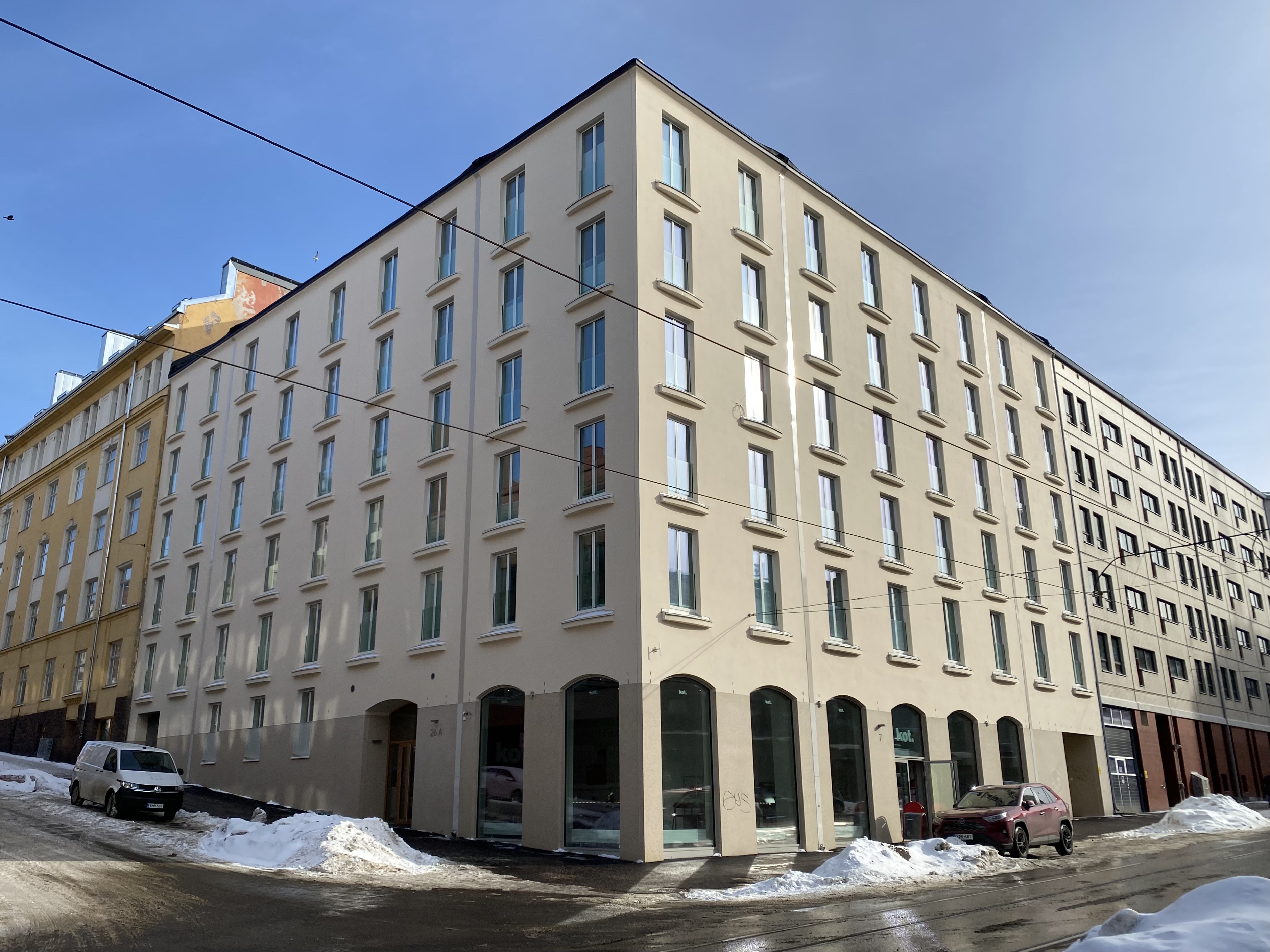 Uusi vaalea asuinkerrostalo Kaarlenkadun kulmassa Kalliossa Helsingissä, talvinen aurinko julkisivulla